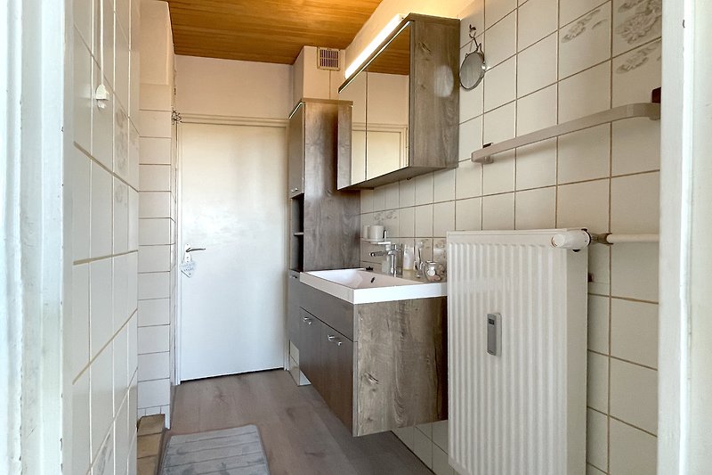 Moderes Badezimmer mit Spiegel, Waschbecken und Armatur.