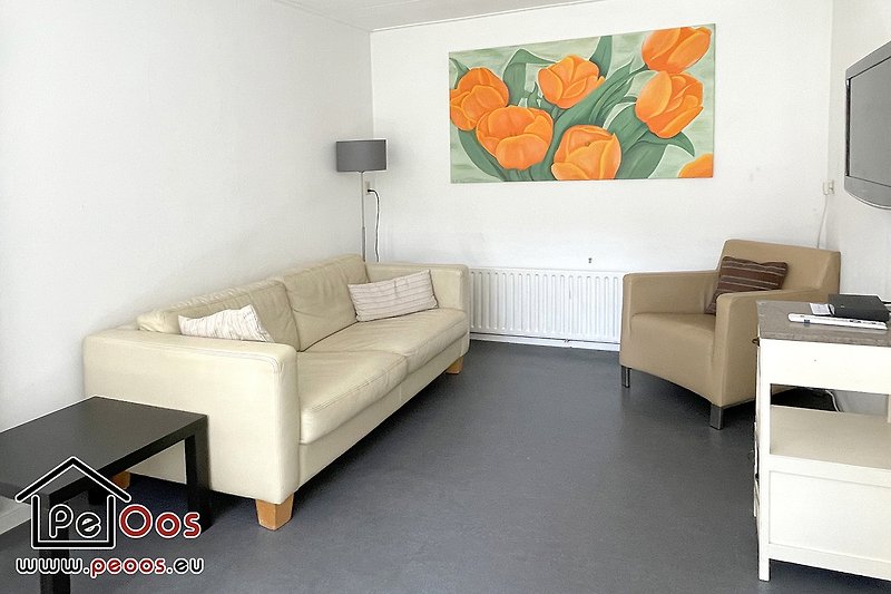 Stilvolles Wohnzimmer mit Kunst, bequemer Couch und Fernseher.