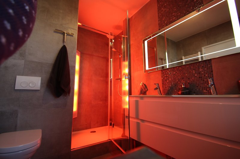 Stilvolles Badezimmer mit lila und orangefarbenen Akzenten, modernen Armaturen und glänzenden Fliesen.