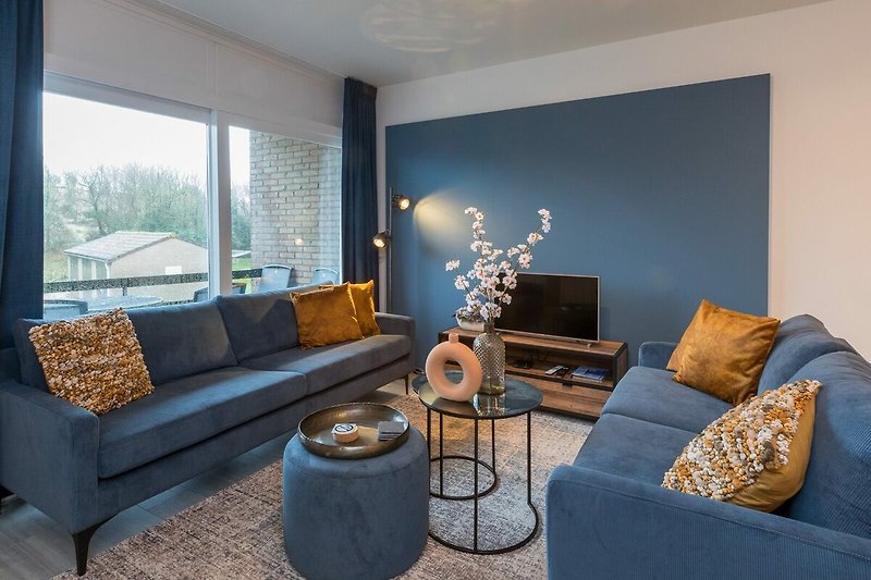 Modernes Wohnzimmer mit bequemer Couch, stilvoller Beleuchtung und Holzmöbeln. Gemütliche Atmosphäre.