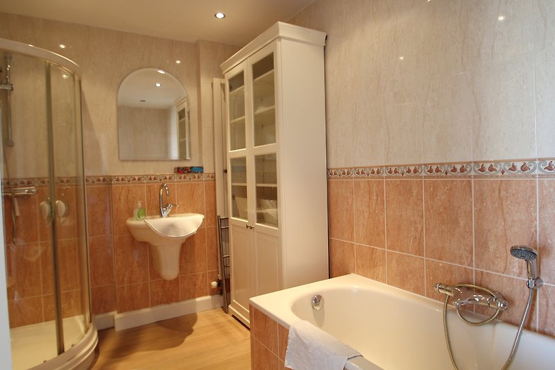 Gemütliches Badezimmer mit Spiegel, Waschbecken und Badewanne.