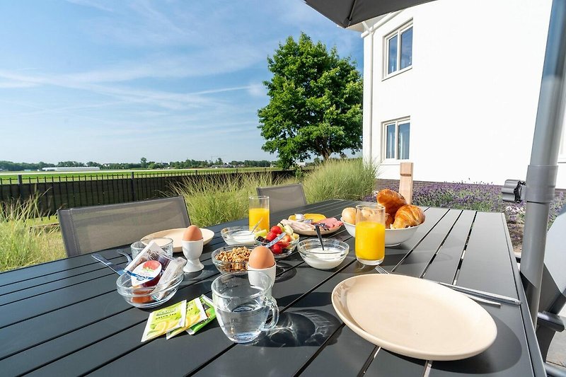 Balkon mit Tisch, Stühlen und Blumen - perfekt für ein Frühstück im Freien!