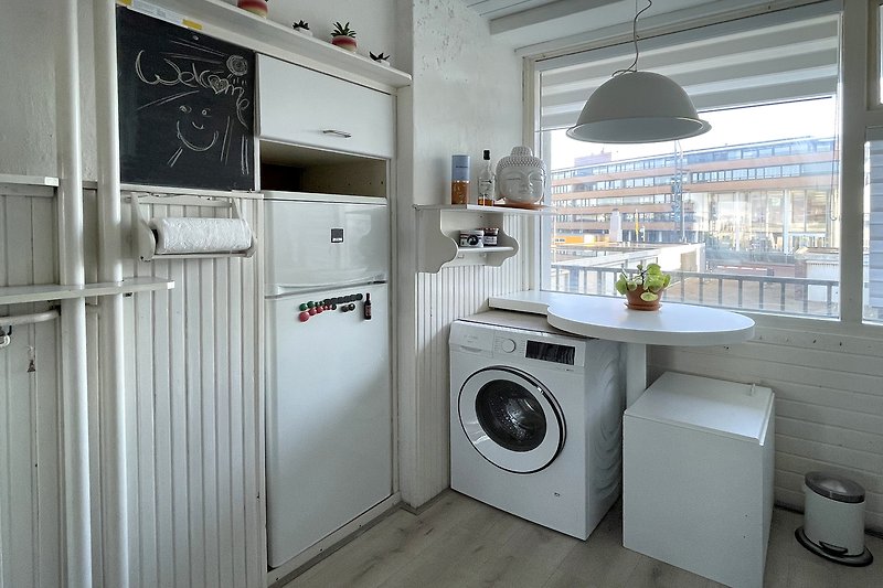 Moderne Küche mit Waschmaschine, Trockner und Küchengeräten.