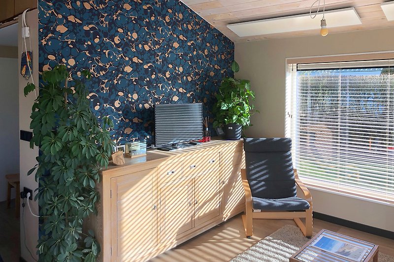 Wohnzimmer mit Holzmöbeln, Pflanzen und Fenstern.