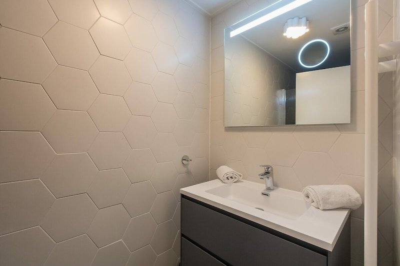 Modernes Badezimmer mit elegantem Spiegel und stilvoller Beleuchtung.