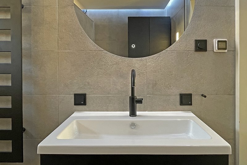 Schönes Badezimmer mit stilvoller Beleuchtung, Spiegel und Fliesen.
