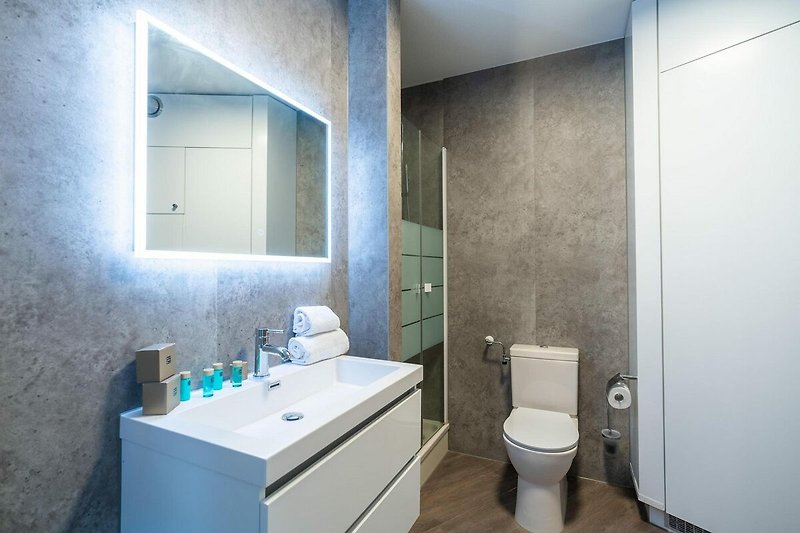 Badezimmer mit lila Akzenten, Toilette, Spiegel und Waschbecken.
