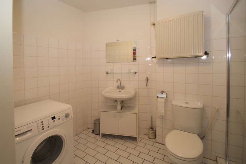 Modernes Badezimmer mit Waschmaschine, Trockner und Toilette.