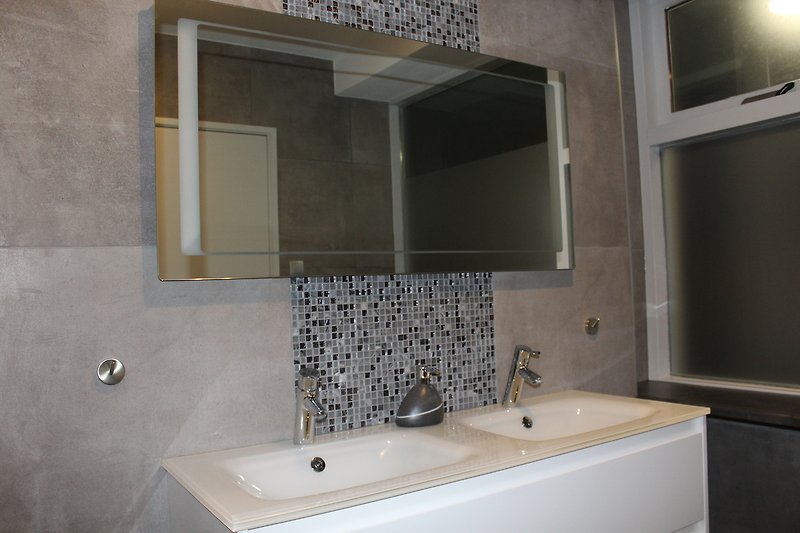 Stilvolles Badezimmer mit elegantem Spiegel und modernen Armaturen.