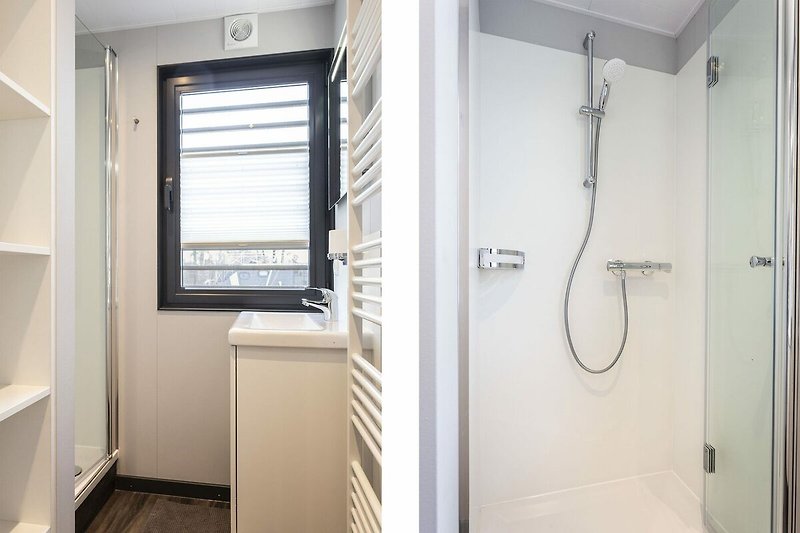 Modernes Badezimmer mit Dusche, Glasduschtür und Metallgriffen.