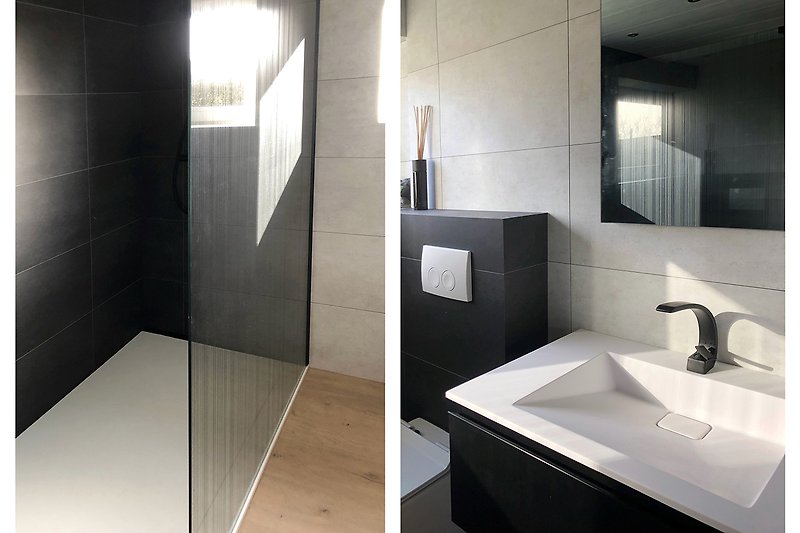 Modernes Badezimmer mit schwarzen Armaturen und Glasdetails.