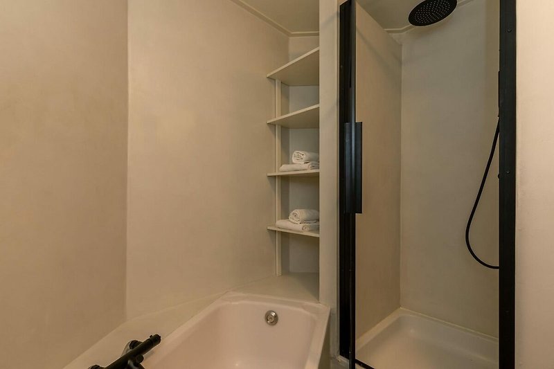 Modernes Badezimmer mit Holzregal, Glasdusche und Badewanne.