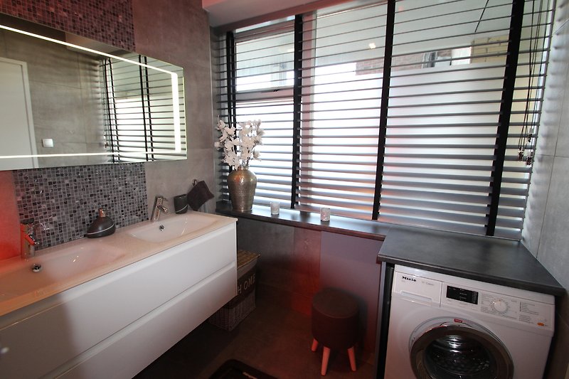 Stilvolles Badezimmer mit moderner Einrichtung und elegantem Spiegel.