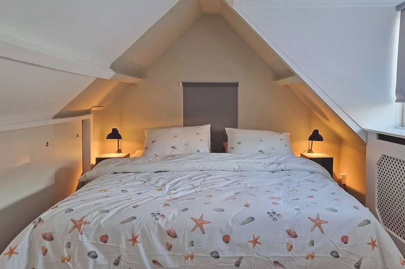 Schlafzimmer mit bequemem Bett, Holzmöbeln und stilvoller Beleuchtung.