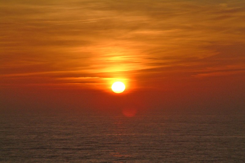 Ruhiger Sonnenuntergang am Meer mit rotem Himmel.