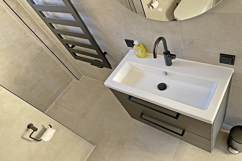 Obenansicht modernes  Badezimmer mit Waschbecken, Spiegel und Fliesen.