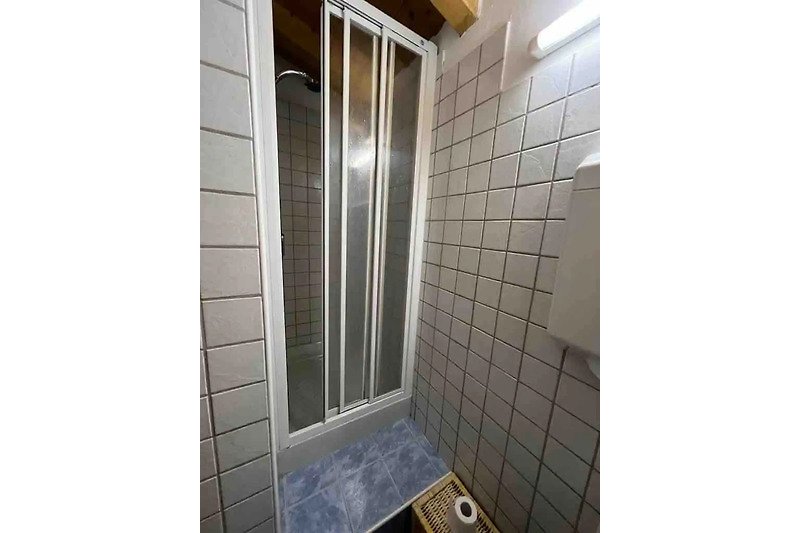 Stylish bathroom with glass shower, modern fixtures, and tile flooring.