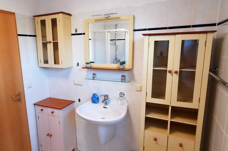 Badezimmer mit Waschbecken, WC, Dusche und Holzmöbeln