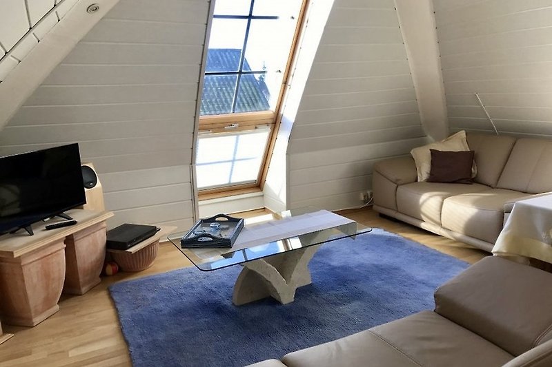 Geräumiges Wohnzimmer mit bequemer Couch und Holzmöbeln.