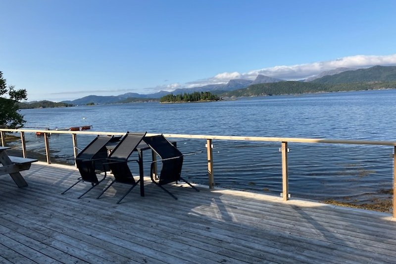Escape to a lakeside retreat with stunning views of the water, sky, and lush green landscape. Relax on the dock or in the outdoor furniture.