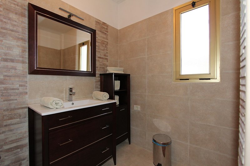 Badezimmer mit Spiegel, Waschbecken und Schrank, in Holzoptik.