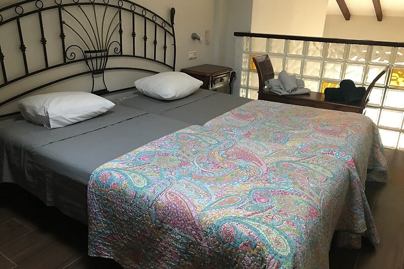 Gemütliches Schlafzimmer mit Bett, Nachttisch und Beleuchtung.