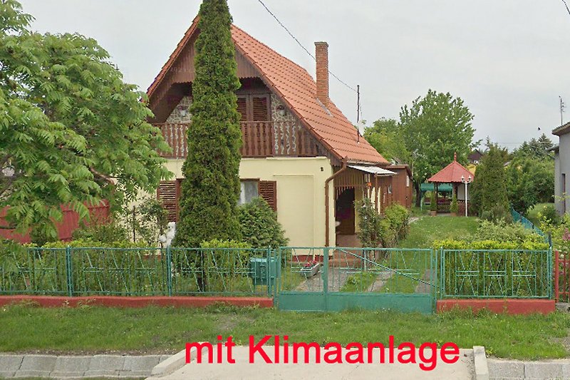 Charmantes Landhaus mit Veranda, umgeben von üppigem Grün.