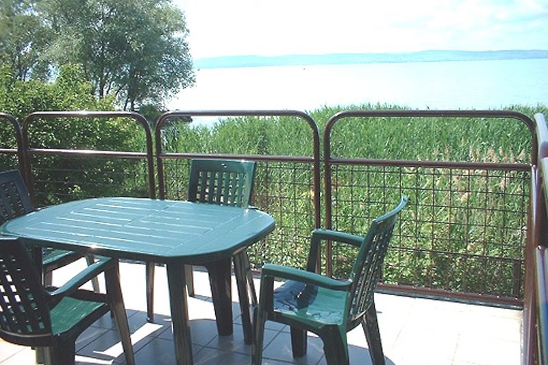 Terrasse mit Gartenmöbeln am Seeufer.