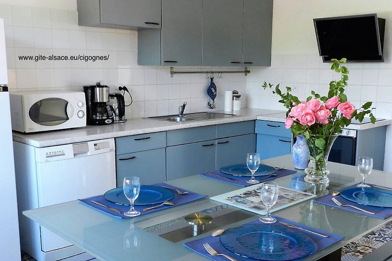 Küche mit lila Blumen, Küchengeräten und Geschirr.