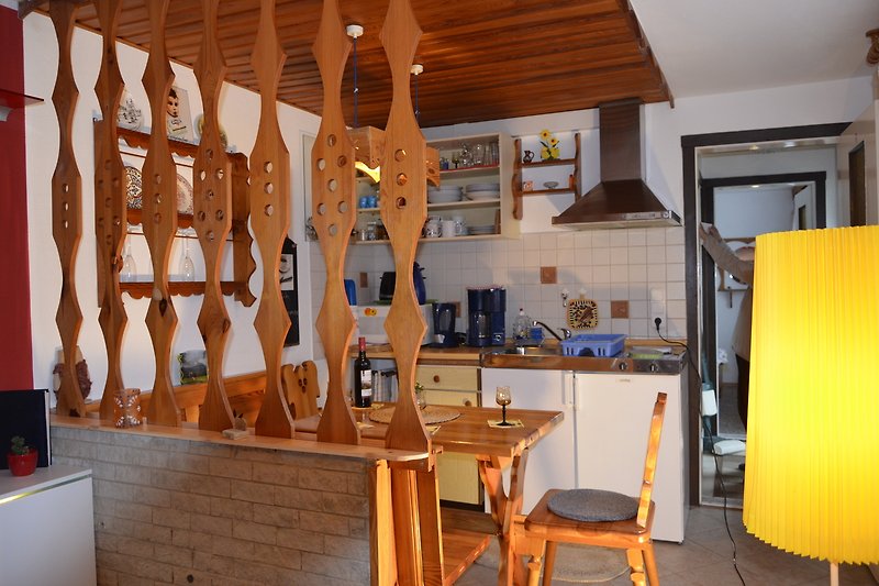 Küche mit Holztisch, Stühlen und Schränken. Gemütliche Beleuchtung.