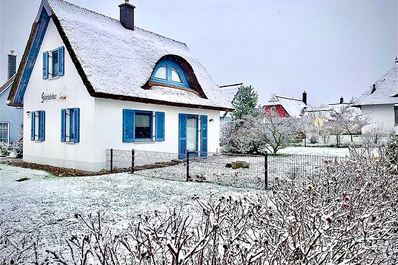 Gemütliches Haus mit verschneitem Dach, malerischer Landschaft und charmantem Garten.