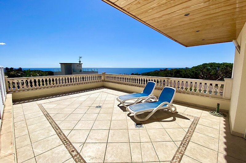 Sonnige Terrasse mit Pool, Liegestühlen und Blick auf die Landschaft.