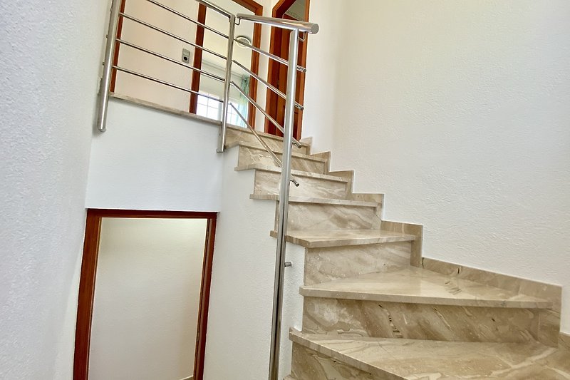 Treppe aus Holz mit Metallgeländer und Glasfenster. Helle Räume.