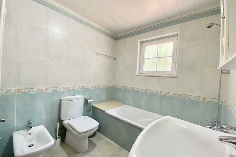 Modernes Badezimmer mit Badewanne, Fenster und Waschbecken. Klare Linien.