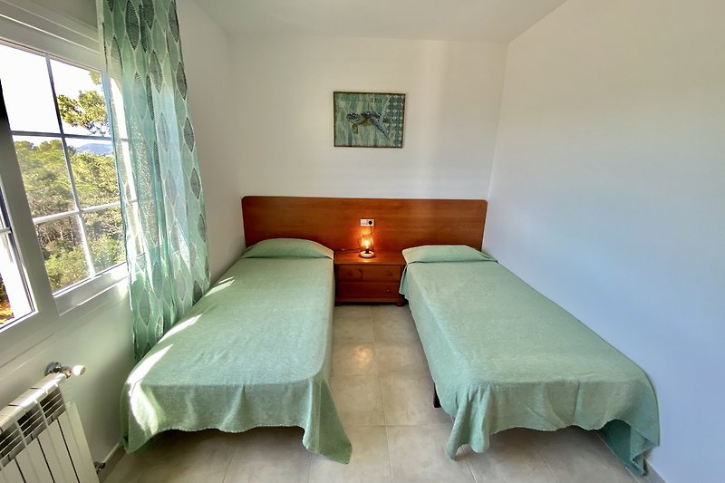 Modernes Schlafzimmer mit gemütlichem Bett, Fenster und Holzmöbeln. Klare Linien.