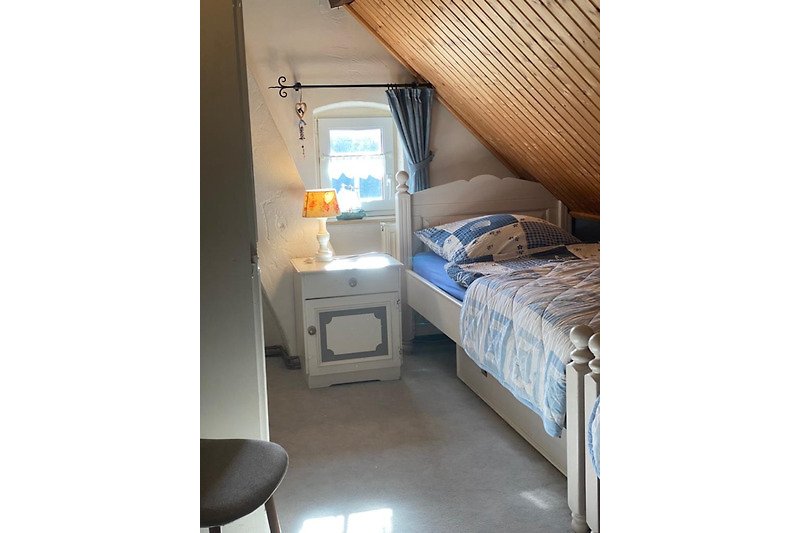 Gemütliches Zimmer mit Holzboden, Vorhängen und bequemem Bett.