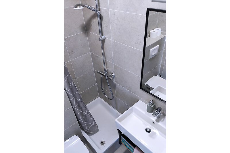 Schönes Badezimmer mit lila Waschbecken, Dusche und Glaswand.