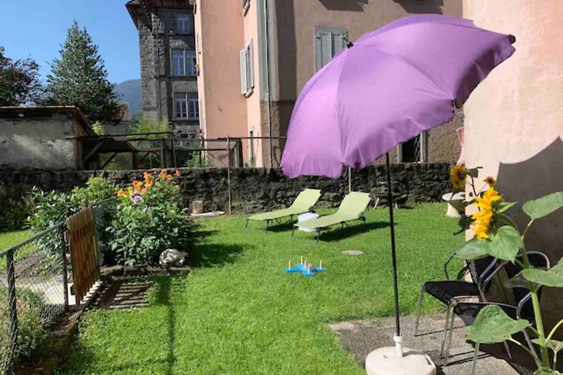Garten mit Sonnenschirm, Stühlen und Blumen - perfekt zum Entspannen!