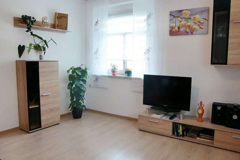 Modernes Wohnzimmer mit Pflanzendeko und Unterhaltungsecke.