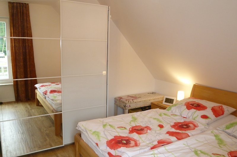 Schlafzimmer mit Doppelbett aus Massivholz (Breite 1,80 m) und Fernseher