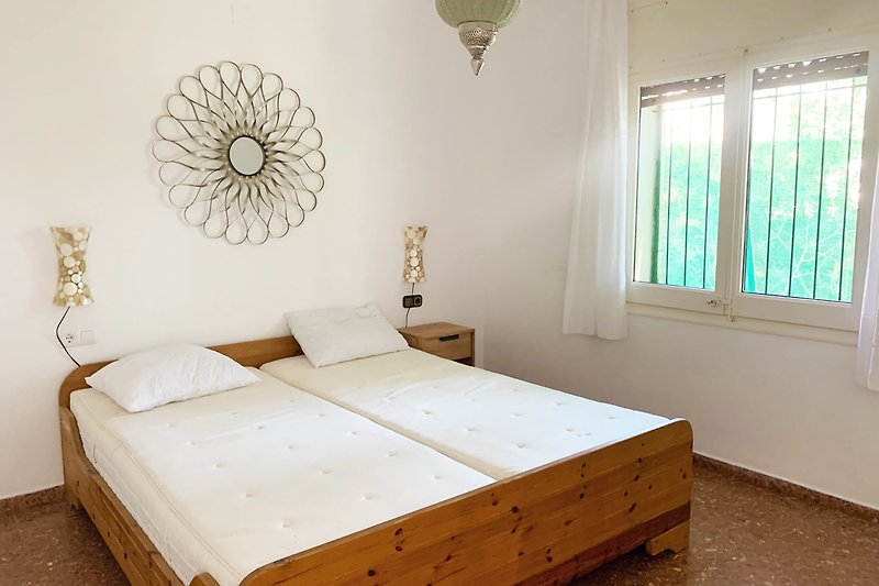 Schlafzimmer mit gemütlichem Bett, Holzmöbeln und Vorhängen.