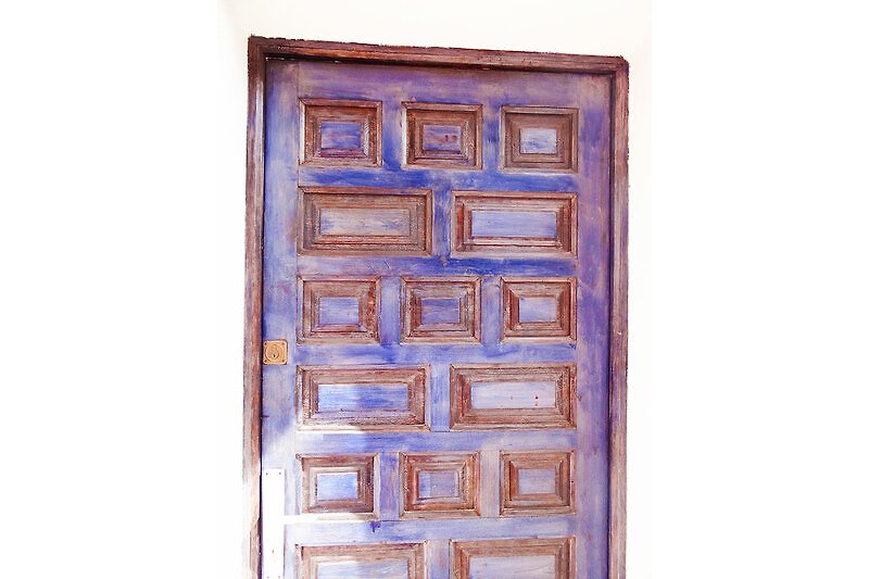 Elegante Holztür mit kunstvoller Verzierung und Metallgriff.