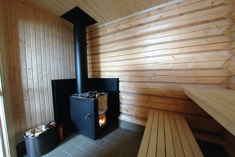 The wood fired sauna is equipped with a hot water tap. A large window towards the lake offers a magnificent view.