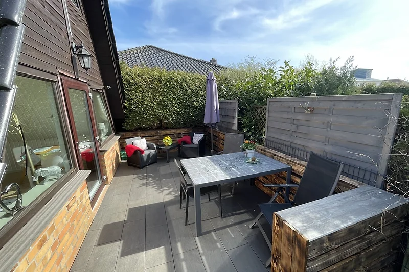 Rustikales Haus mit Holzfassade, grünem Garten und Terrasse.