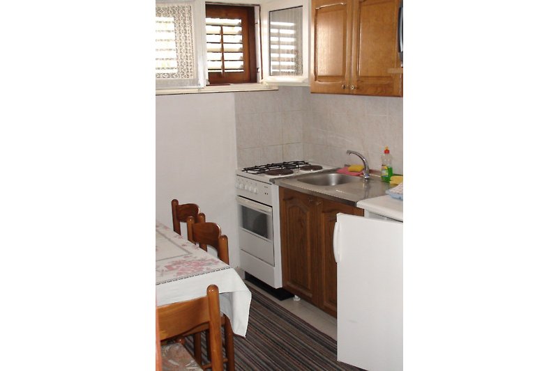Moderne Küche mit weißen Schränken, Holzboden und Fenster.