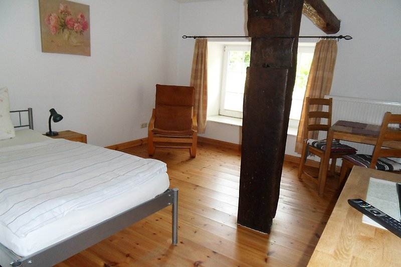 Komfortables Schlafzimmer mit Bad und mit stilvollem Holzmobiliar und gemütlicher Einrichtung.