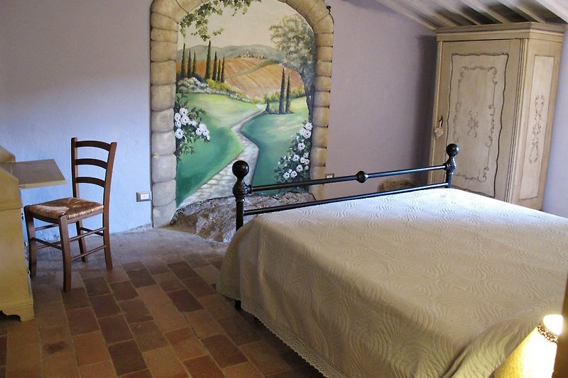 Lo más destacado de la casa: habitación doble con un mural de trompe-l'oeil que representa un paisaje toscano ficticio.
