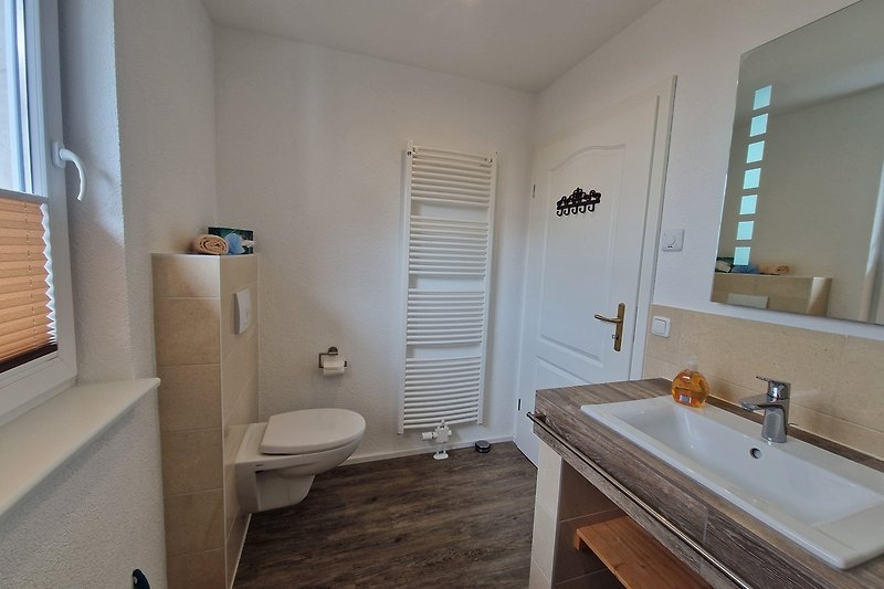 Badezimmer mit lila Badezimmerschrank, Holzboden und Fenster.
