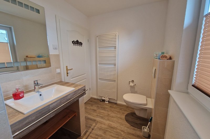 Gemütliches Badezimmer mit lila Waschbecken und Holzboden.
