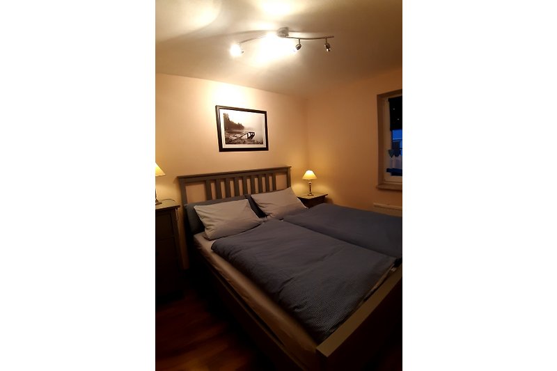 Ein stilvolles Schlafzimmer mit Holzboden, gemütlichem Bett und elegantem Lampenschirm.